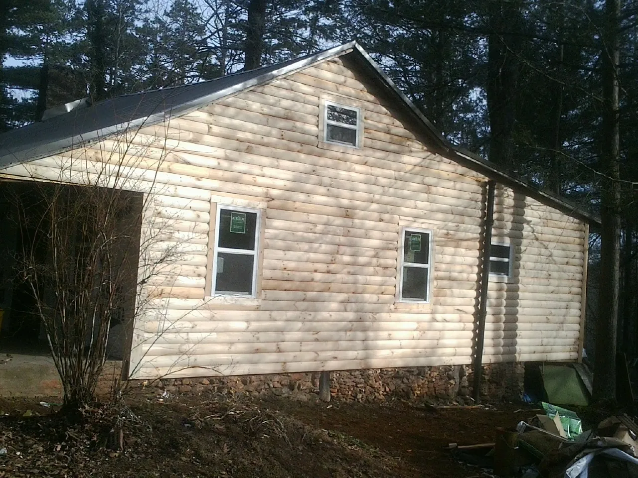New log siding and dark metal roofing on a gable end in Jermyn