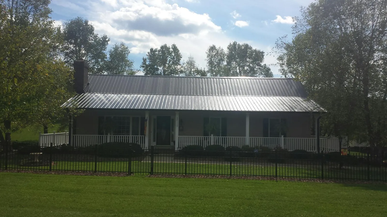 Gray metal roof on a brick ranch with a full width front porch — Gutter Guard Installation work by our crew in Jermyn
