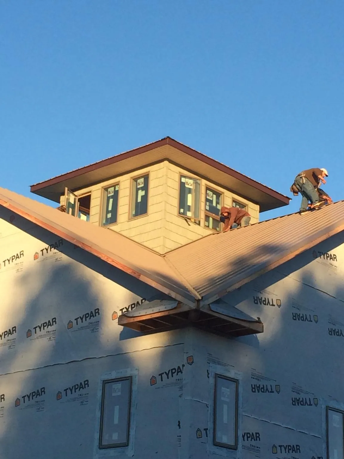 Roofers working around a rooftop cupola on a new metal roof at sunset — Roof Waterproofing in Jermyn by Roofing Brothers